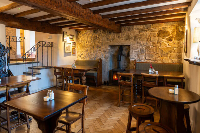 Interior on The Cross Keys pub in Llanfynydd - wooden beamed ceiling, lit woodburner in the alcove with table and chairs