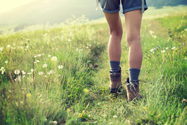 Young woman hiker walking on trail in grassland