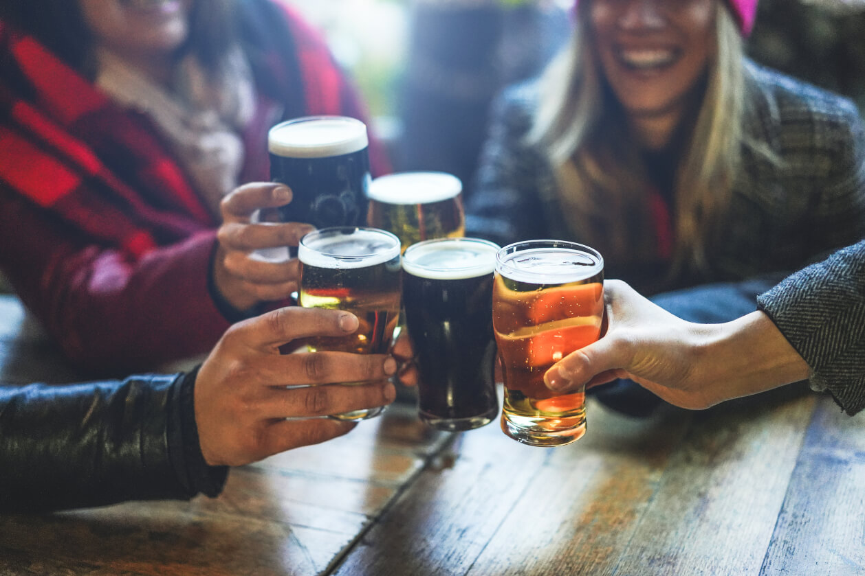 a group of adults clinking pint glasses containing cider and lager