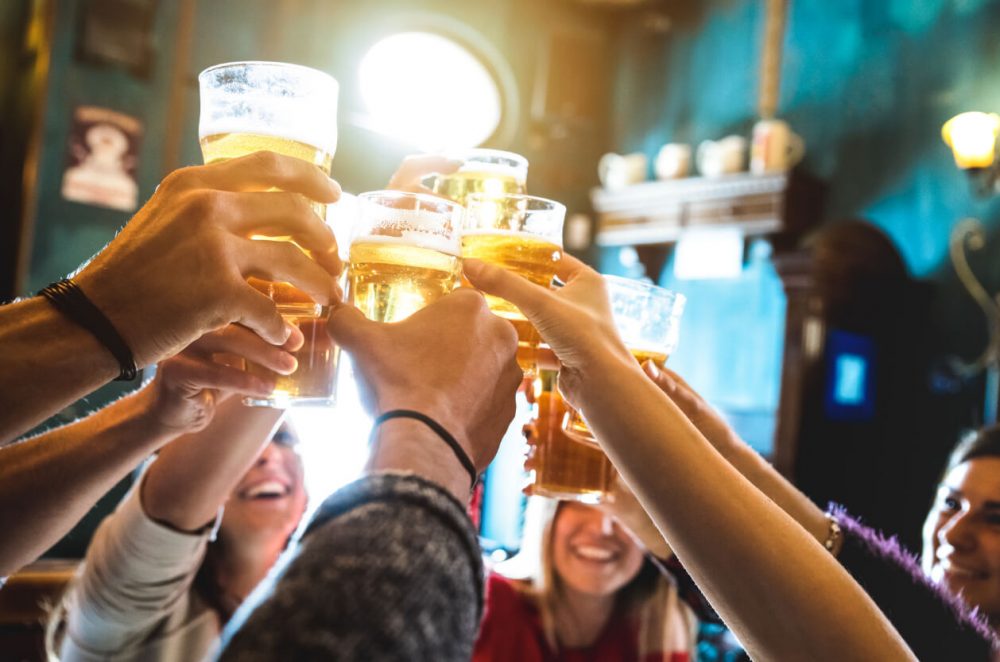 a group of friends clinking pint glasses