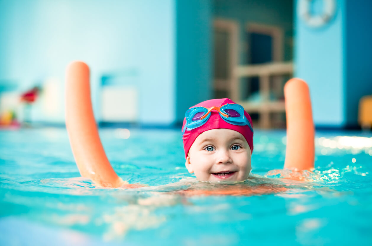 child swimming with pool noodle