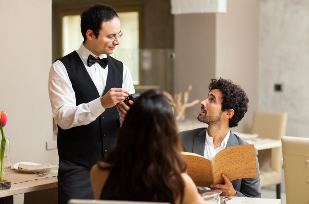 couple being served by a waiter in restaurant