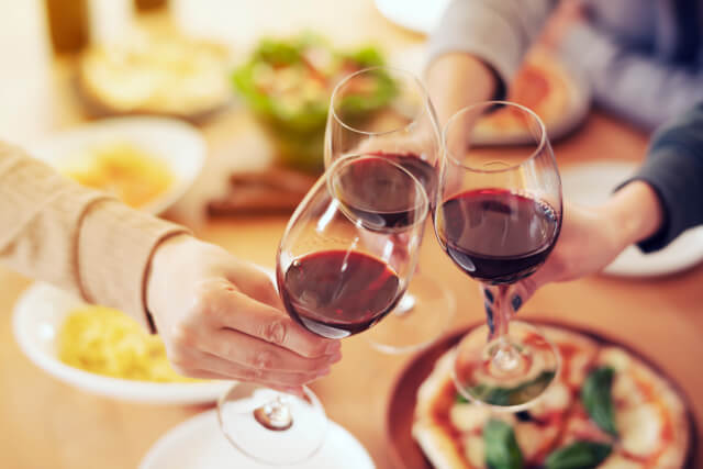 group clinking glasses filled with red wine