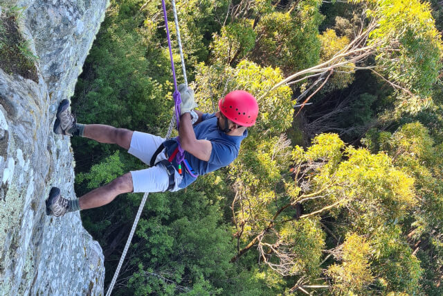 guy abseiling off rugged cliff