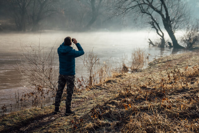 man birdwatching at a body of water