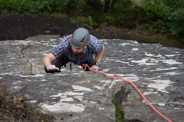 man rock climbing up crag