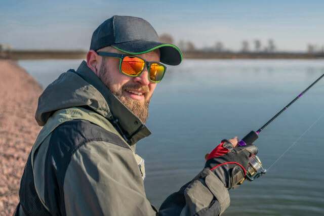 man wearing sunglasses angling on large body of water