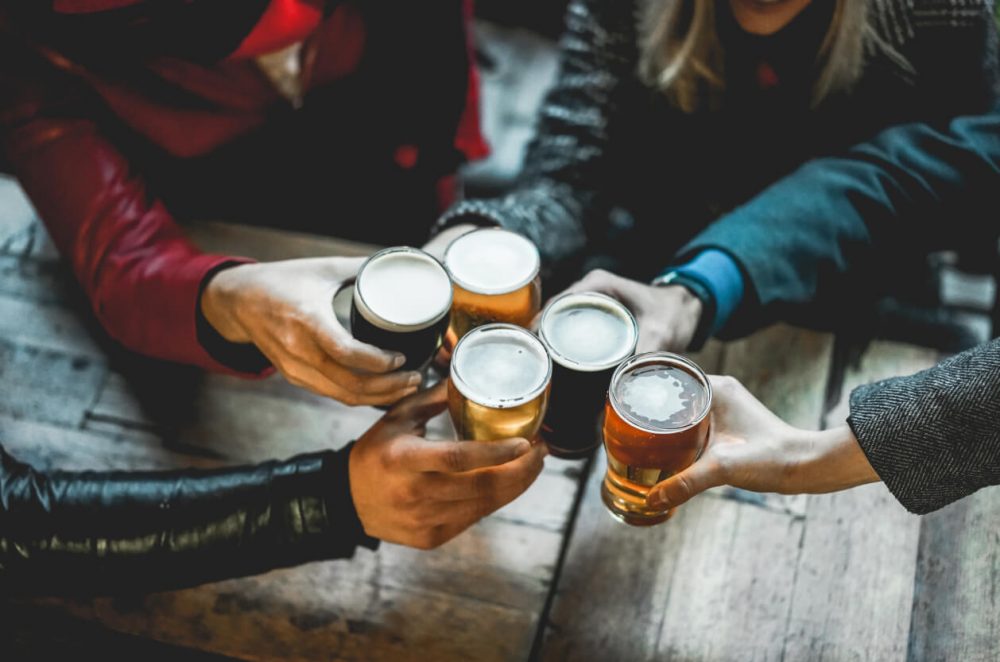 people clinking beers in glasses