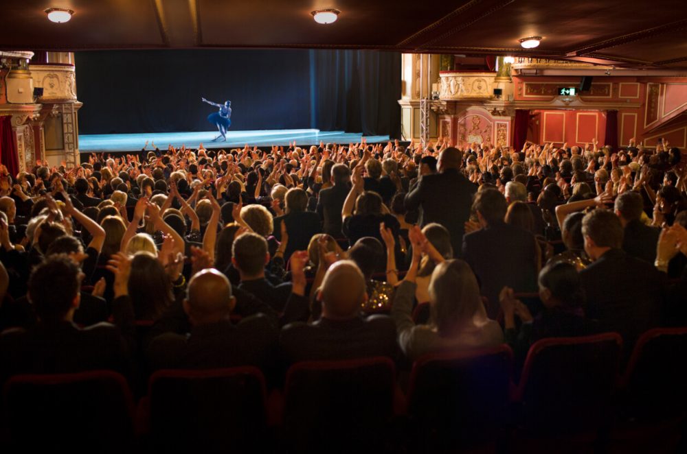 perfomer at a theatre with an applauding audience