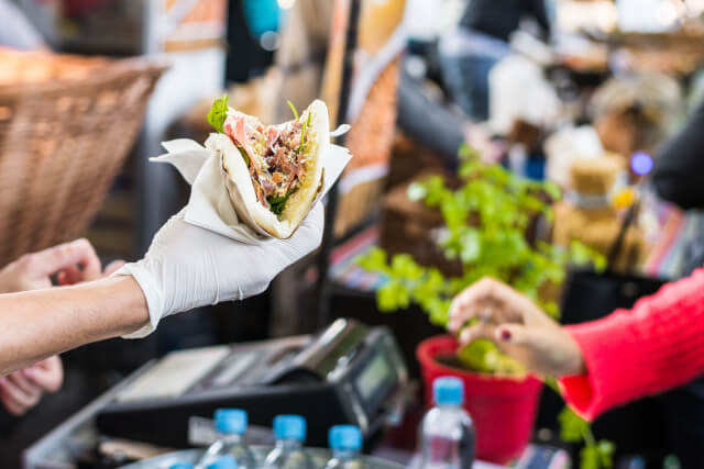 person serving taco to customer at food stall