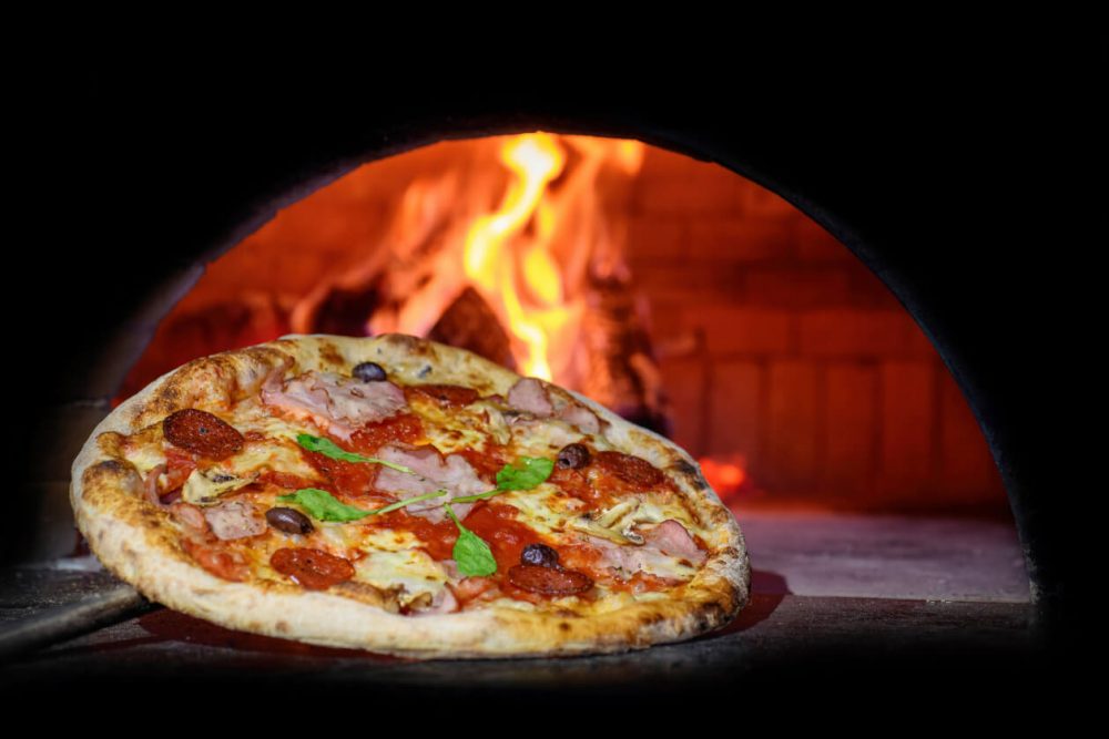 pizza being taken out of pizza oven