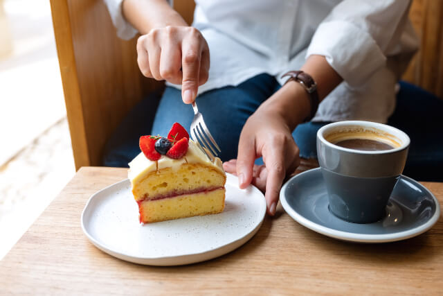 woman eating cake and coffee in cafe