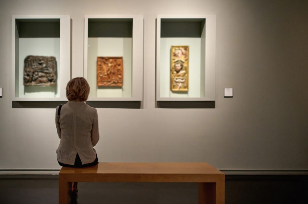 woman sat on bench in art gallery